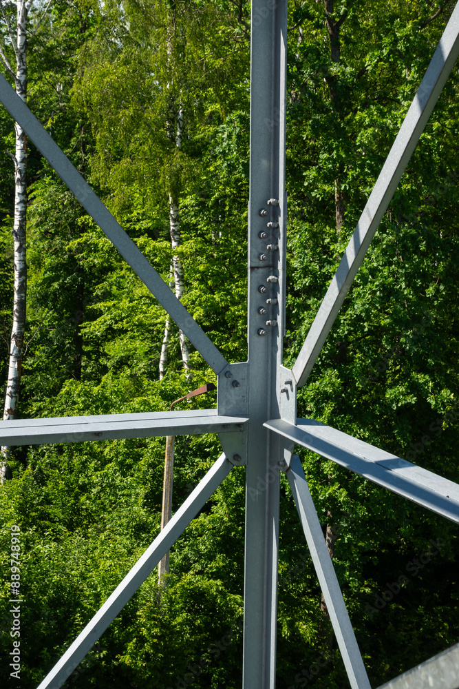 Bolted connections of steel elements of the observation tower. Construction details of galvanized steel against a green trees background
