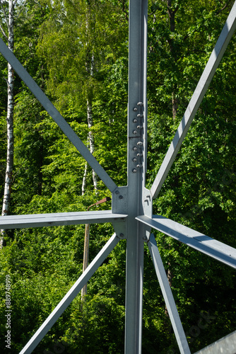 Bolted connections of steel elements of the observation tower. Construction details of galvanized steel against a green trees background