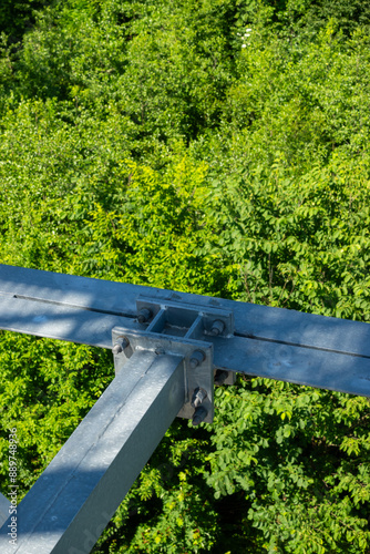 Bolted connections of steel elements of the observation tower. Construction details of galvanized steel against a green trees background
