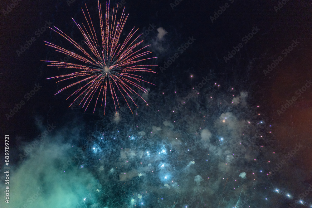 Green and purple fireworks with smoke over the black sky.