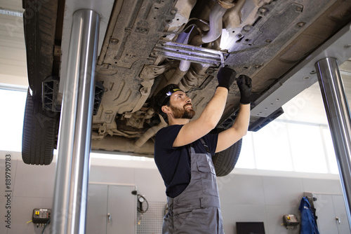 Canvastavla Skilled auto mechanic repairing car undercarriage in service garage