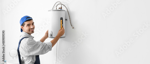 Young plumber installing bo...