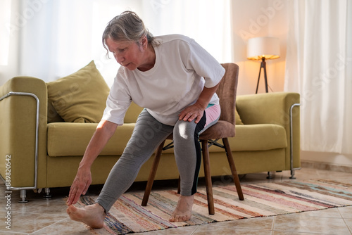Senior caucasian woman doing doing yoga at home on sofa