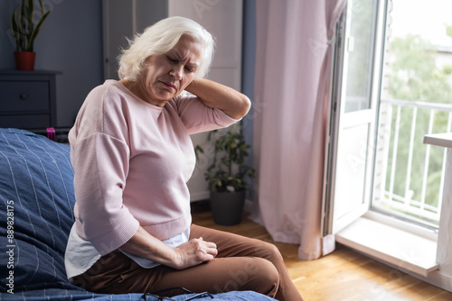  senior woman suffering from neck pain sitting at home alone photo