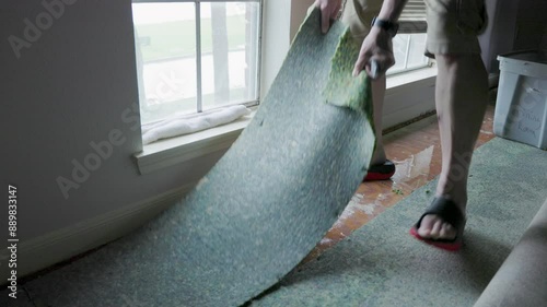 man removing wet carpet from hurricane damage