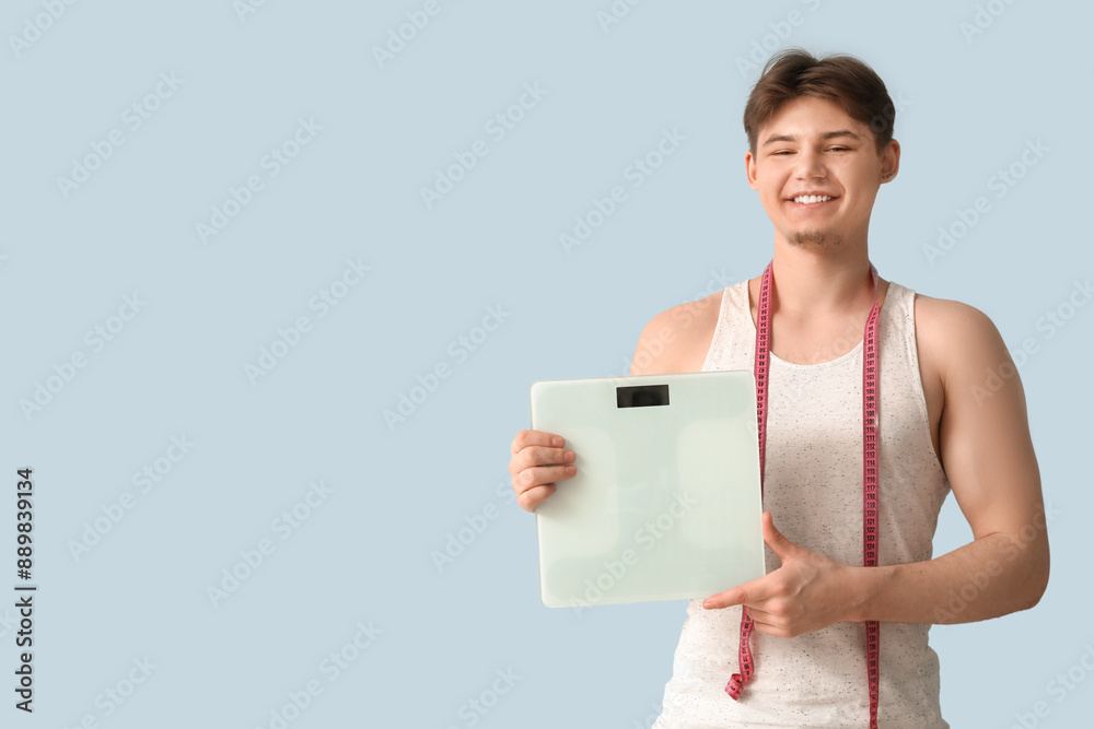 Sporty young man with scales and measuring tape on light background. Weight loss concept Sporty young man with scales and measuring tape on light background. Weight loss concept