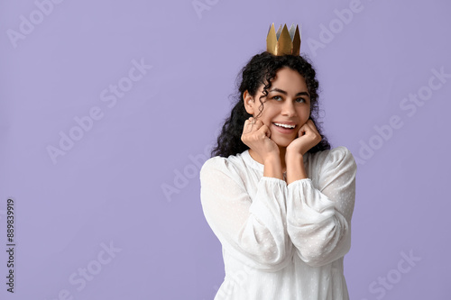 Beautiful young African-American woman in paper crown on lilac background photo