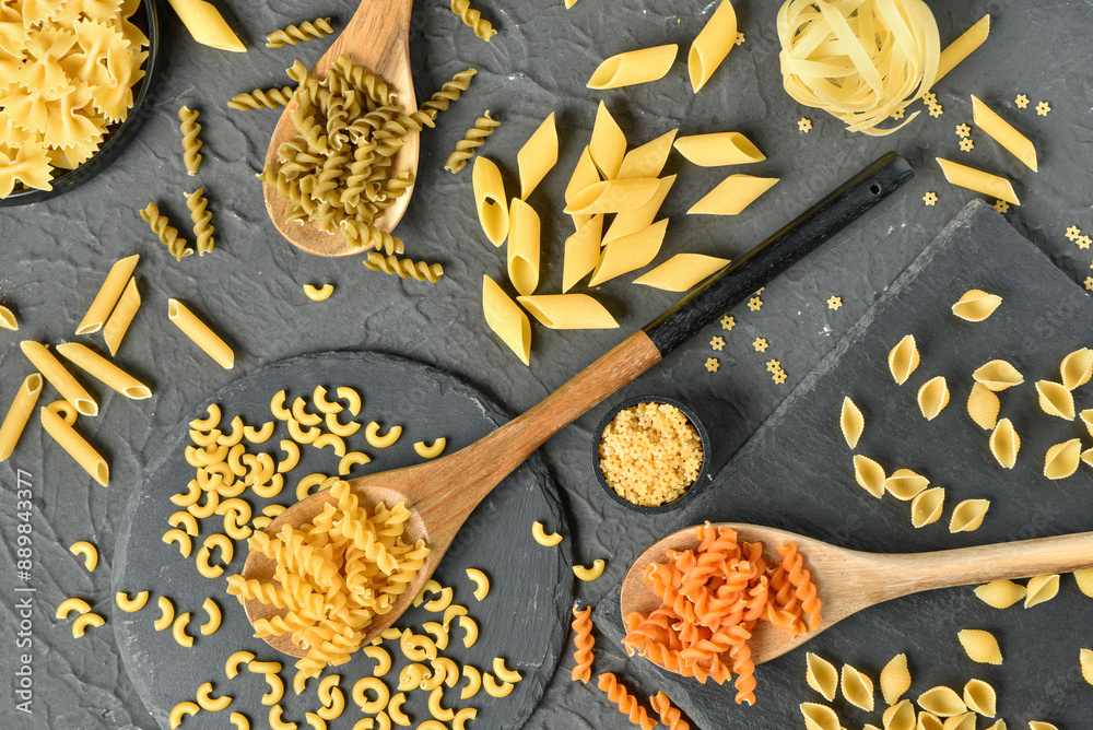 Composition with different tasty uncooked pasta on dark background