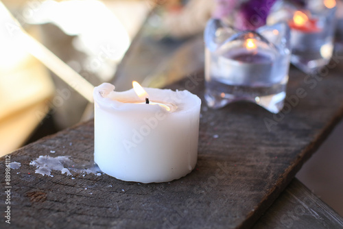 White burning candle on wooden plank. Melted Wax Candles Burning. Romantic mood on holiday vacation.