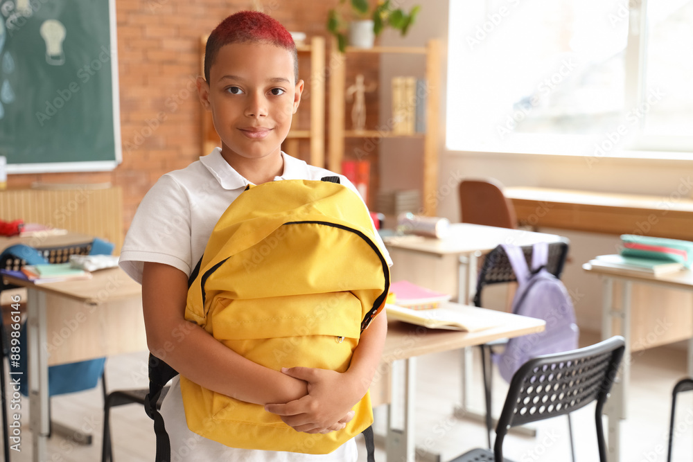 Fototapeta premium Little African-American schoolboy with yellow backpack in classroom