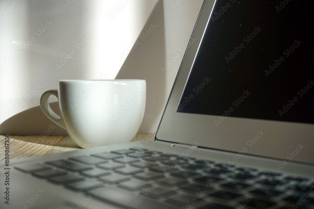 Fototapeta premium White cup of coffee on the table and laptop