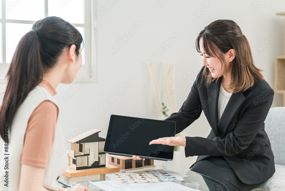 設計図・図面・タブレットを見ながらマイホームの説明をする設計士のビジネスウーマンと女性客
