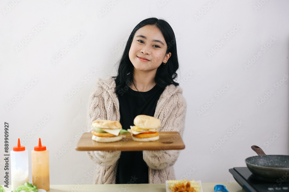 Asian Young Woman Holding A Wooden Cutting Board With Tasty Homemade Burgers And Smile Asian Young Woman Holding A Wooden Cutting Board With Tasty Homemade Burgers And Smile