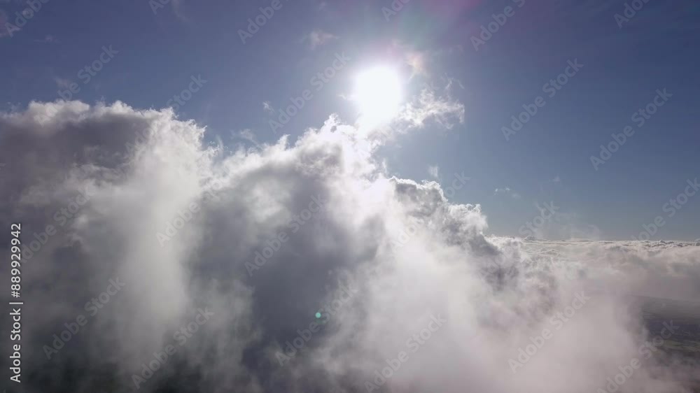 Billowy voluminous white clouds slowly cover the blue sky, while the sun rays create a halo over Maui, Hawaii Billowy voluminous white clouds slowly cover the blue sky, while the sun rays create a halo over Maui, Hawaii