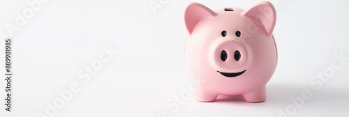 A pink piggy bank sits on a white surface, its coin slot in focus as a coin is about to be inserted