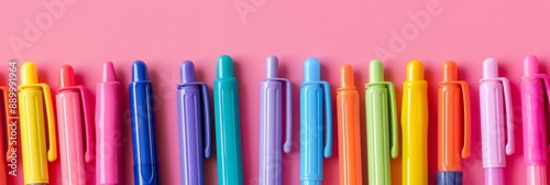 A close-up shot of an array of colorful felt tip pens arranged horizontally against a solid pink background, suggesting a back-to-school theme