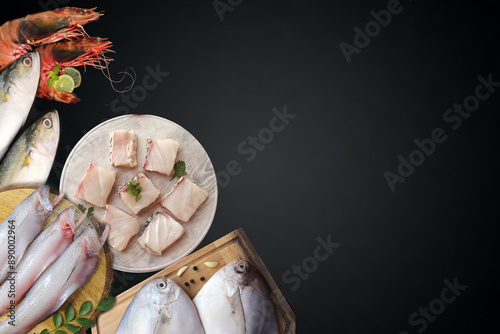 Assorted fish over black background. Mackerel, bangda, Bombay duck or bombil, Prawns, and silver pomfret banner. fresh fish website banner with copy space. photo