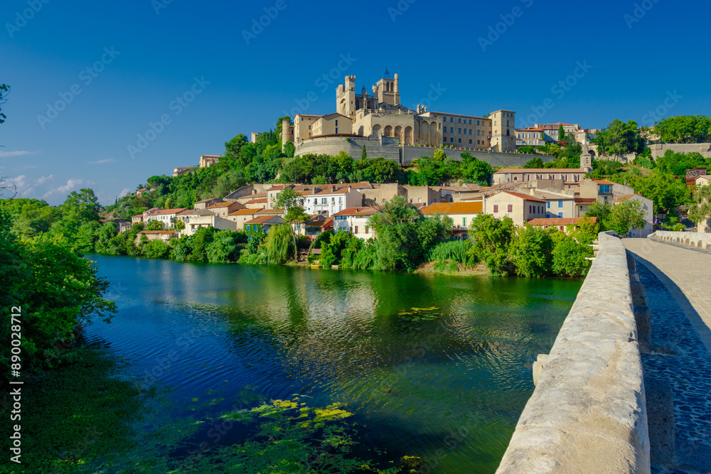 Obraz premium Cathedral Saint-Nazaire-A river runs through a town with a castle in the background