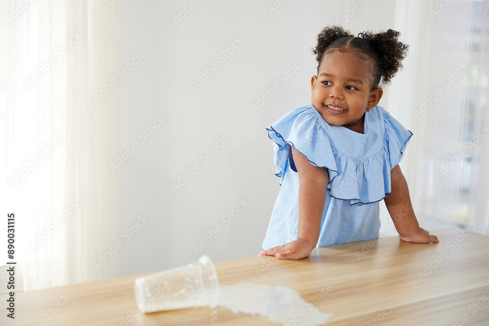 little African girl spilling milk on the table little African girl spilling milk on the table