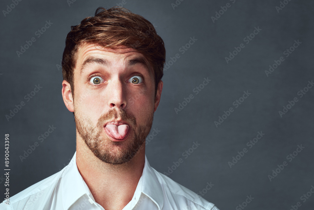 Tongue out, portrait and man in studio, funny and mockup for comic of employee, joke and expression. Grey background, space and face of person, crazy or emoji of journalist, playful and job in agency Tongue out, portrait and man in studio, funny and mockup for comic of employee, joke and expression. Grey background, space and face of person, crazy or emoji of journalist, playful and job in agency