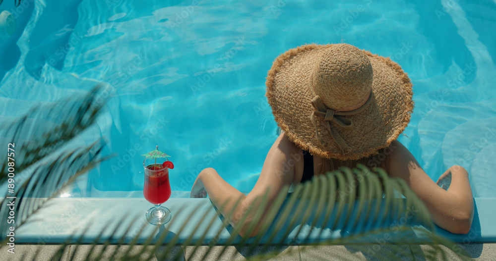 Φωτογραφία Teenage girl in a straw hat relaxing by the pool, with palm leaves gently swayin