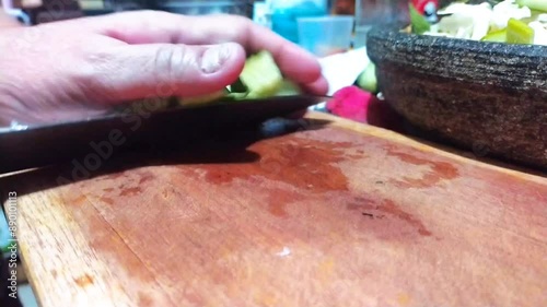 cutting cucumber on a cutting board as one of Lotek's cooking ingredients. Lotek is a salad made from Javanese (Indonesian) vegetables with peanut sauce photo