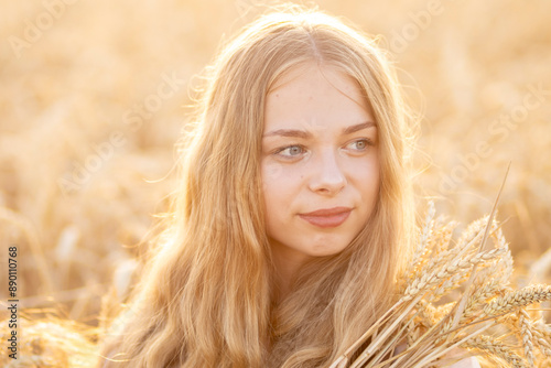 A beautiful Ukrainian girl on a wheat field in the rays of the sun