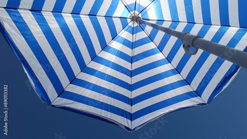 striped beach umbrella on a blue sky background