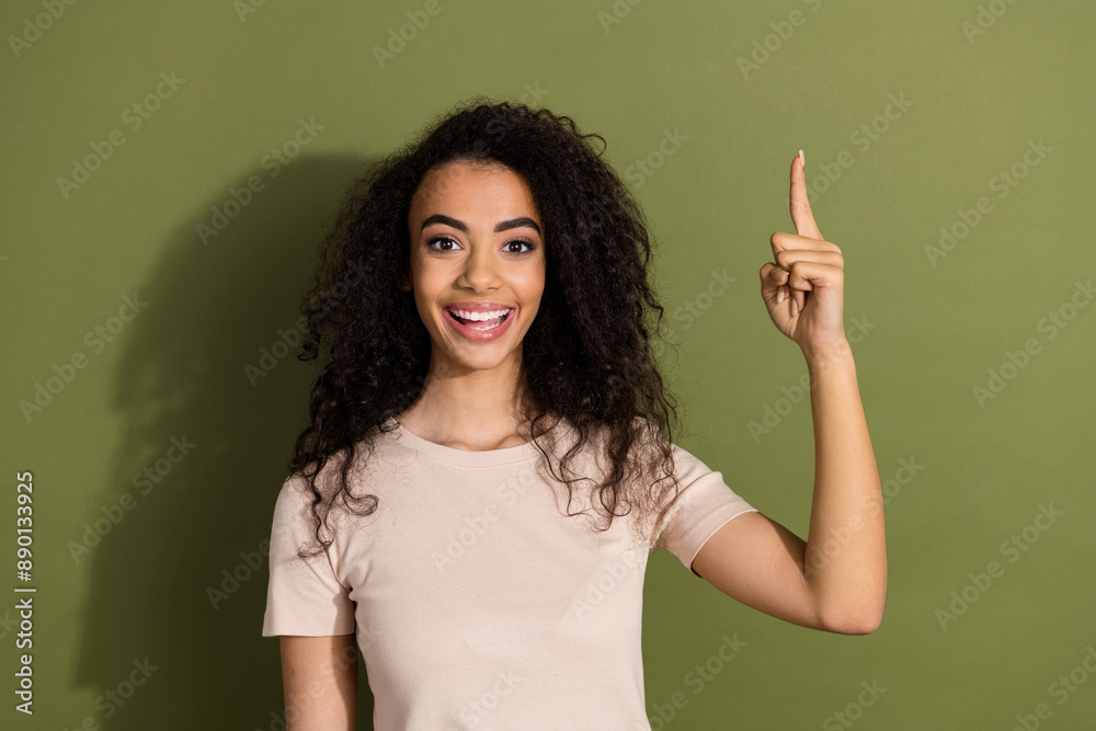Photo of smart girl with wavy hairstyle dressed beige t-shirt raising directing at sale empty space isolated on khaki color background Photo of smart girl with wavy hairstyle dressed beige t-shirt raising directing at sale empty space isolated on khaki color background