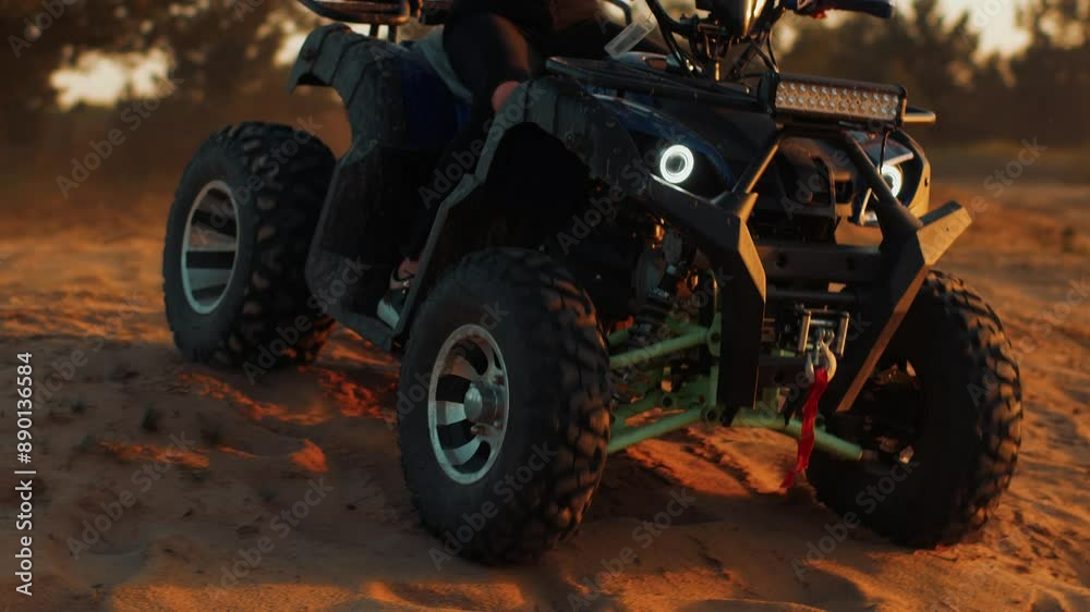Man rides an atv with his headlights on along sandy hilly area. Slow motion. Close-up of all-terrain vehicle. Concept of freedom and joy Man rides an atv with his headlights on along sandy hilly area. Slow motion. Close-up of all-terrain vehicle. Concept of freedom and joy