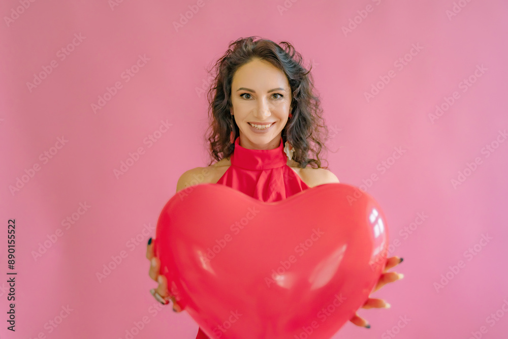 A woman is holding a red heart balloon. She is smiling and she is happy. Concept of joy and love, as the heart symbolizes affection and warmth. A woman is holding a red heart balloon. She is smiling and she is happy. Concept of joy and love, as the heart symbolizes affection and warmth.