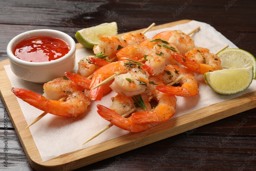 Skewers with delicious grilled shrimps served on wooden table, closeup Skewers with delicious grilled shrimps served on wooden table, closeup