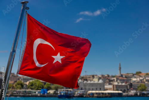 The Turkish flag waves in the wind with the city of Istanbul in the background. Turkish national flag waving in istanbul against blue sky. photo