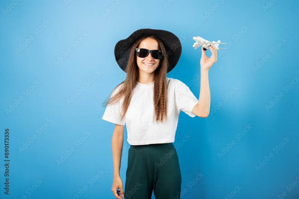 Summer travel, teenage student with an airplane in her hands, curly hair and luggage at the airport, young person planning a vacation. Summer travel, teenage student with an airplane in her hands, curly hair and luggage at the airport, young person planning a vacation.