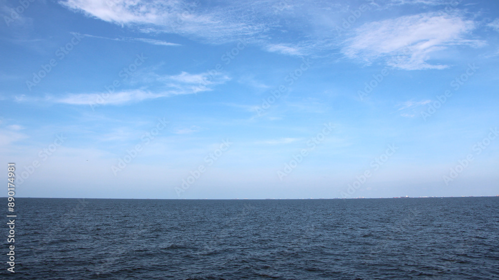 The expanse of sea stretches under a blue sky with white clouds
The expanse of sea stretches under a blue sky with white clouds