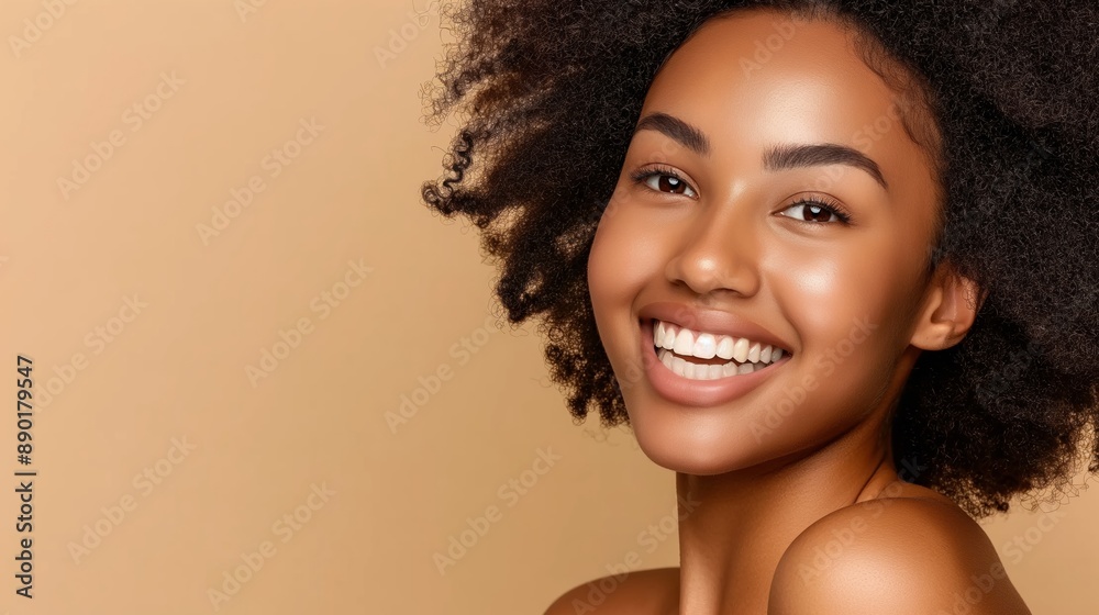 A woman with curly hair is smiling and looking at the camera. She has a natural, glowing look to her face A woman with curly hair is smiling and looking at the camera. She has a natural, glowing look to her face