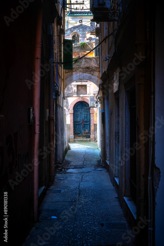 Sehr enge und dunkle Gasse in Korfu Stadt mit Blick auf eine Tür mit Rundbogen