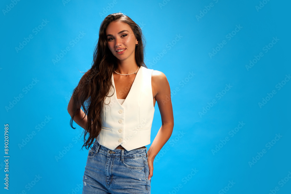 Young woman dressed stylish casual outfit smiling looking at camera against blue studio background. Trendy colors. Concept of human emotions, fashion and style, business.