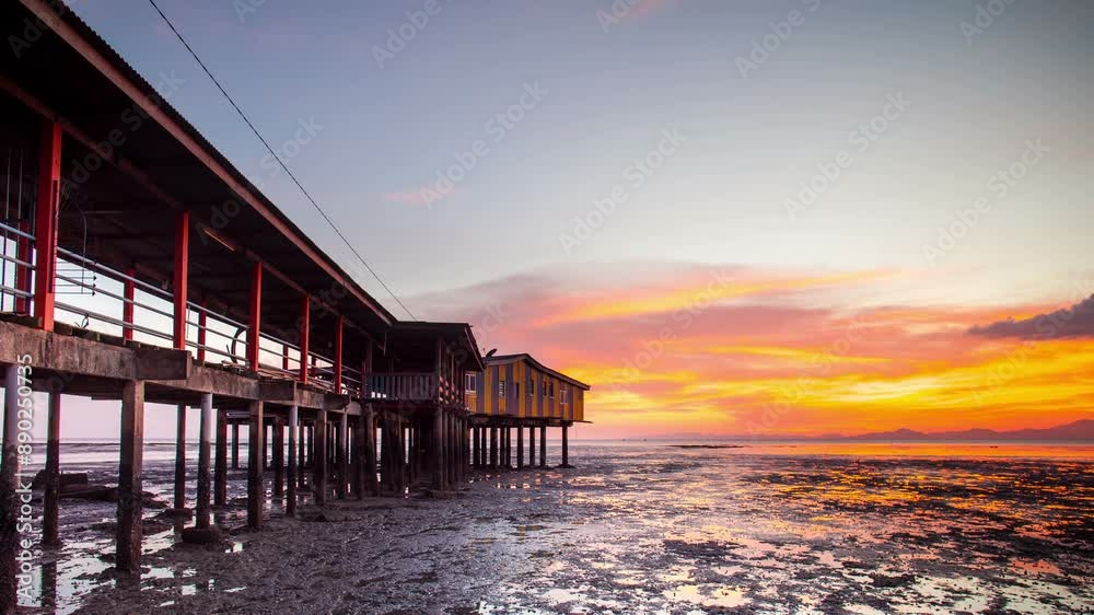 Timelapse of a beautiful orange sunset sky over the sea. The sun sets behind the houseboat.