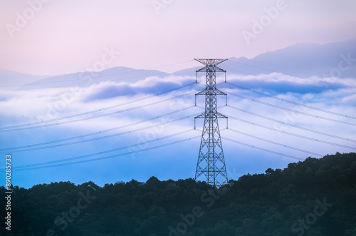 A high voltage tower and a sea of raging, tumbling clouds on a summer morning. View of the mountains surrounding Emerald Reservoir. Xindian District, Taiwan. photo