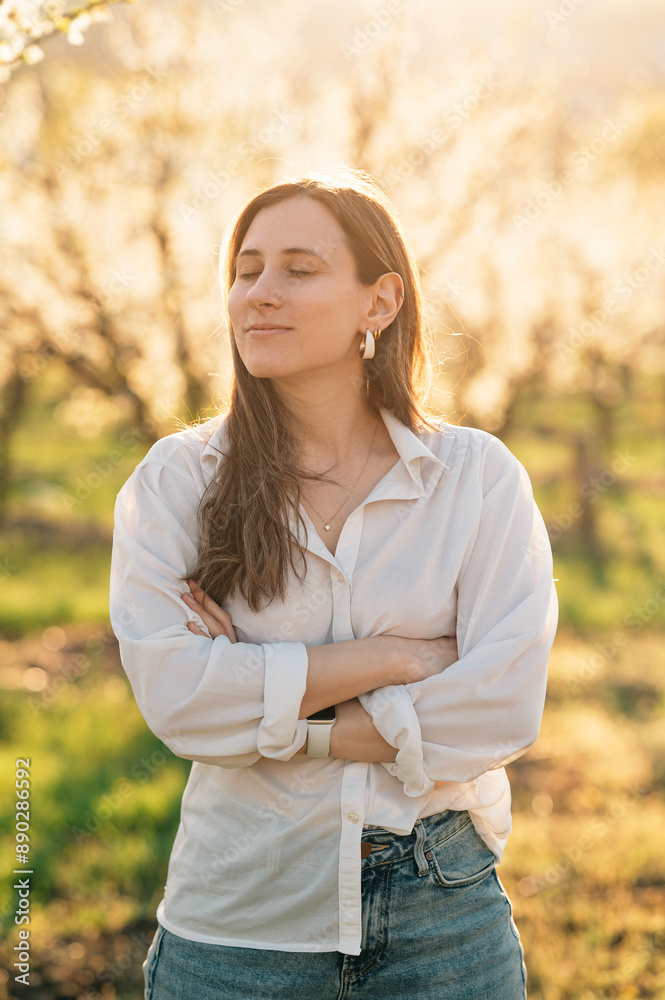 Portrait of a woman standing amidst blooming trees, basking in sunlight with eyes closed, exuding calmness. Portrait of a woman standing amidst blooming trees, basking in sunlight with eyes closed, exuding calmness.