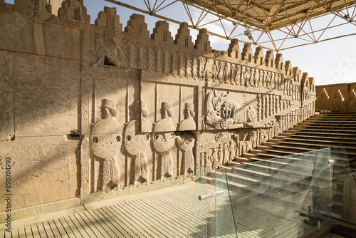 Bas-relief carvings of embossed soldiers beside a lion hunting a bull on one of the staircases in Persepolis, a UNESCO World Heritage Site located in northeast of Shiraz, Iran
