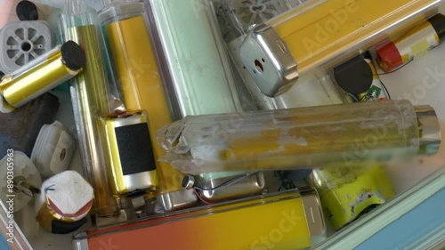 Collection of discarded vapes, internal components and batteries shot over a white plastic sheet. One vape has been blurred in software to remove branding.