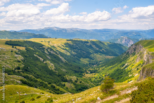 A serene landscape featuring a valley encircled by sunlit mountains