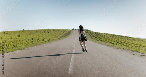 Young woman in black dress roller skating outdoors on sunny day