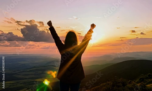 Silhouette of a person feeling strong and empowered, standing tall on the top of a mountain at sunrise