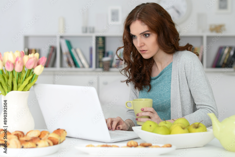 Woman is working with laptop sitting at the table and eating Woman is working with laptop sitting at the table and eating