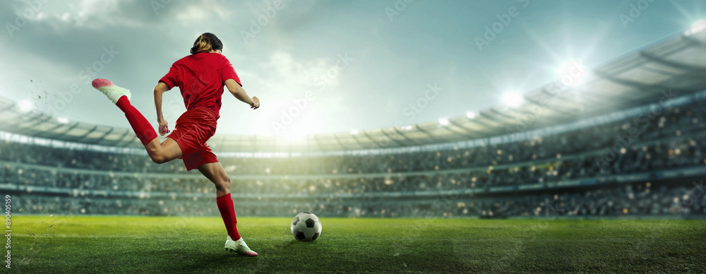 Female soccer player in red kicks ball on stadium field. Arena filled with enthusiasts, and field brightly lit with sunlight and spotlights. Concept of sport, championship, team game, tournament. Ad Female soccer player in red kicks ball on stadium field. Arena filled with enthusiasts, and field brightly lit with sunlight and spotlights. Concept of sport, championship, team game, tournament. Ad