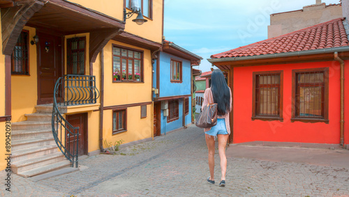 A dark-haired woman wearing mini short jeans walking on the street -  Historical Homes and street - Odunpazari - Eskisehir photo