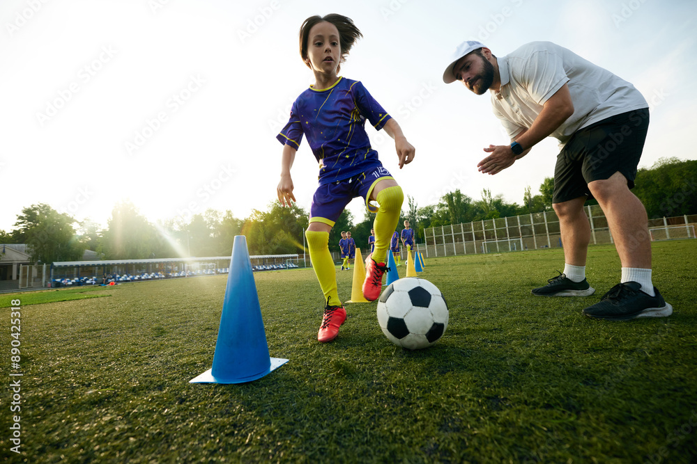 Obraz premium Male sport coach guiding young player through dribbling drill, encouraging and commentating. Focus and concentration. Concept of sport, childhood, education, achievement, active lifestyle